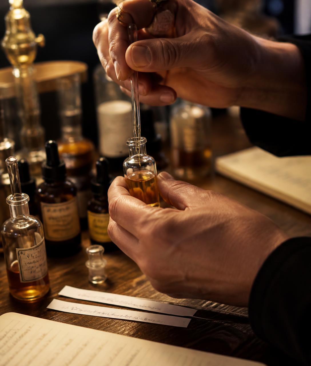 Hands blending fragrance oil into a small glass vial